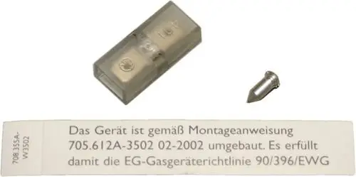 Ein transparentes Gehäuse mit einem kleinen Metallstift und einer Gebrauchsanweisung auf einem Papier, das die Umrüstung eines Bosch Gasdruckwächters beschreibt.